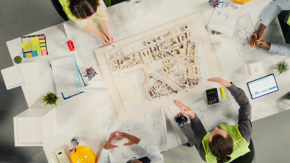 Vista central de arquitectos e ingenieros coordinando planos de un proyecto urbano bajo una misma lógica